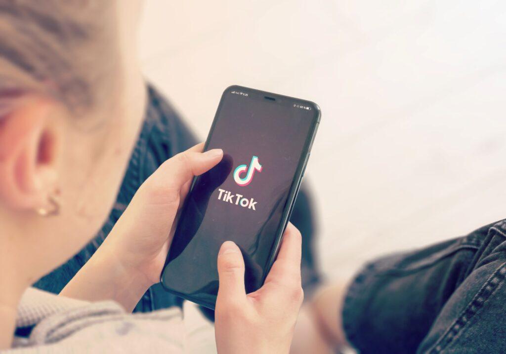 Person hält ein Smartphone mit der geöffneten TikTok-App in der Hand.