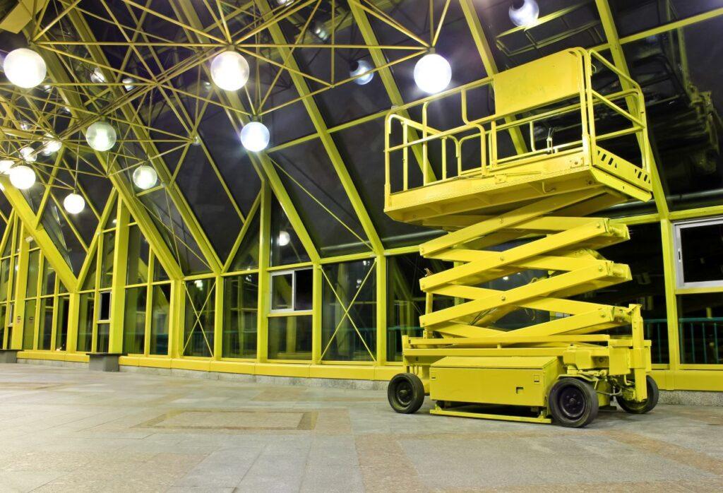 Gelbe Scherenarbeitsbüh e in moderner Halle mit Glasdach bei Innenmontage