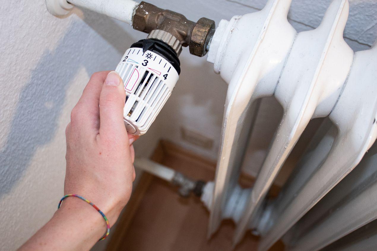 Hand stellt Thermostat am Heizkörper ein – Energie sparen bei hohen Heizölpreisen in Hamburg