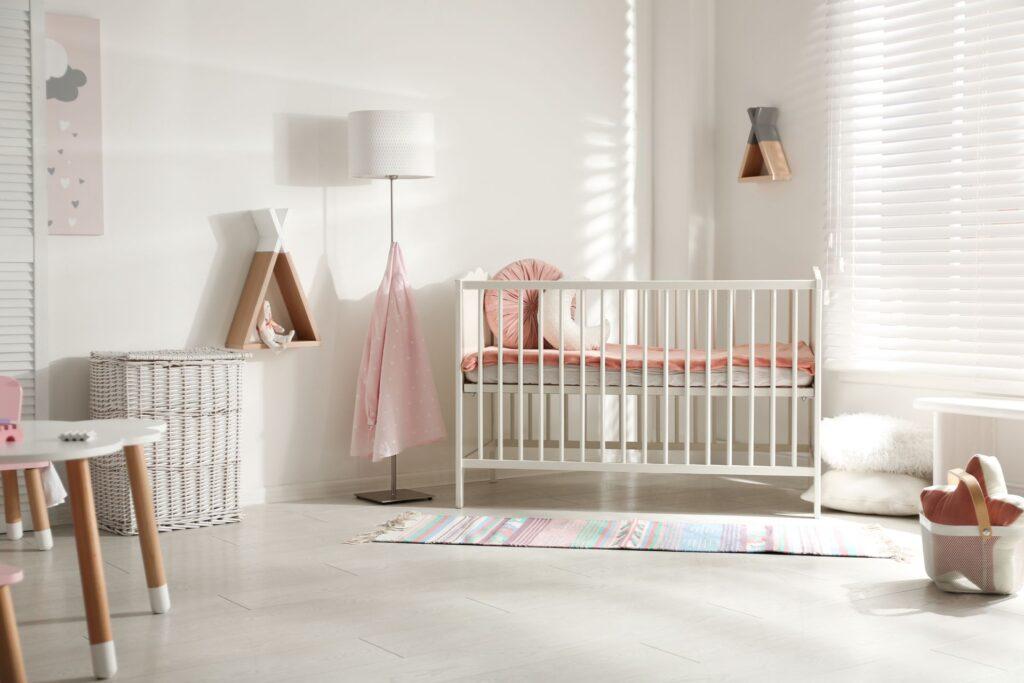 Modernes Babyzimmer mit weißen Möbeln, rosa Textilien und weichem Tageslicht