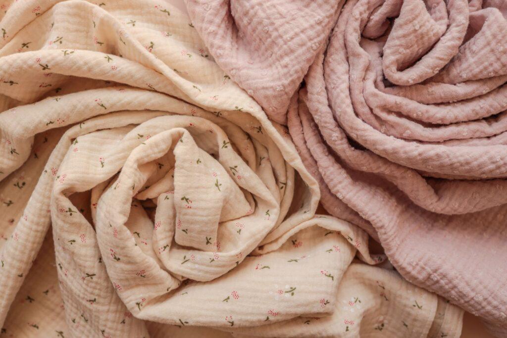 Weich strukturierter rosa Stoff aus Musselin auf hellem Untergrund, ideal fuer Babytextilien